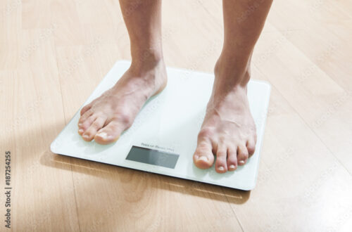 Healthy diet, fitness and weight loss concept. The legs of a young woman on the scales. Checking the weight.