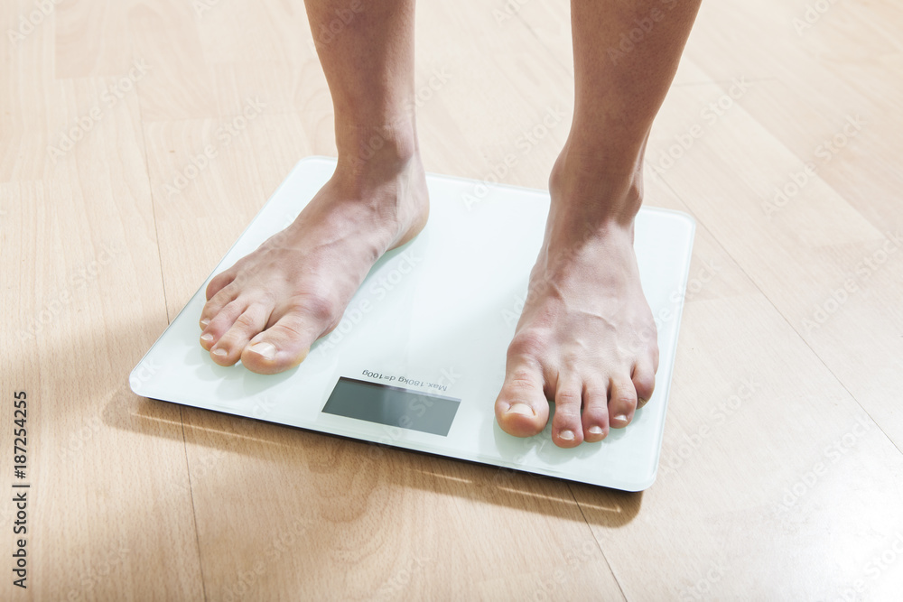 Healthy diet, fitness and weight loss concept. The legs of a young woman on the scales. Checking the weight.