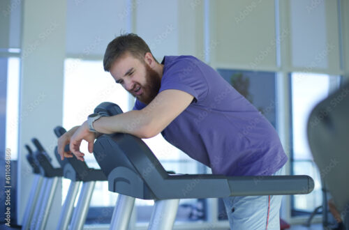 Why training doesn’t work. Tired exhausted young man feeling bad, unhealthy, unwell during run on treadmill in the gym